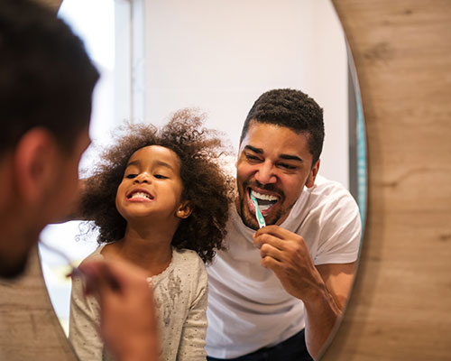 father and child brushing teeth together