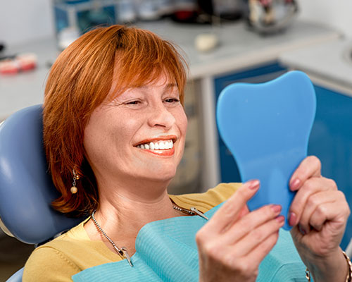 woman looking at teeth in molar shaped mirror